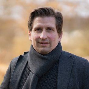 Grüner Fraktionär Julian Arends, vor unscharfer gelblicher Vegetation