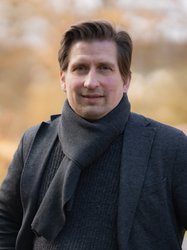 Grüner Fraktionär Julian Arends, vor unscharfer gelblicher Vegetation