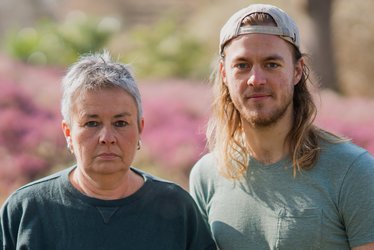 Grüne Fraktionsvorsitzende Suse Stobbe und Julian Schlumberger, vor unscharfem rötlich-grünen Hintergrund