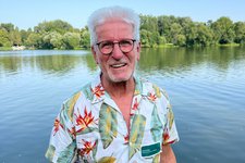 Horst Roth vor einem See mit Bäumen am Horizont