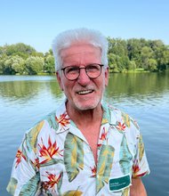 Horst Roth vor einem See mit Bäumen am Horizont