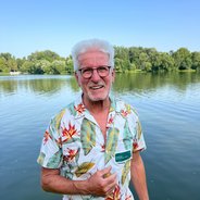 Horst Roth vor einem See mit Bäumen am Horizont