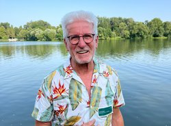Horst Roth vor einem See mit Bäumen am Horizont
