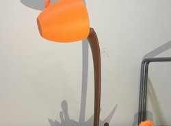 3D-Druck Symbolbild: orangene Tasse die braune Flüssigkeit ausschüttet, vor hellem Hintergrund