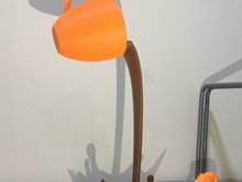 3D-Druck Symbolbild: orangene Tasse die braune Flüssigkeit ausschüttet, vor hellem Hintergrund