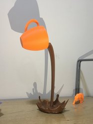 3D-Druck Symbolbild: orangene Tasse die braune Flüssigkeit ausschüttet, vor hellem Hintergrund