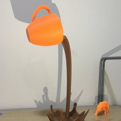 3D-Druck Symbolbild: orangene Tasse die braune Flüssigkeit ausschüttet, vor hellem Hintergrund