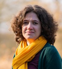 Grüne Fraktionärin Leonie Engelbert, vor unscharfer gelblicher Vegetation