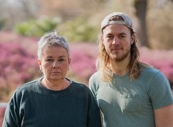 Grüne Fraktionsvorsitzende Suse Stobbe und Julian Schlumberger, vor unscharfem rötlich-grünen Hintergrund