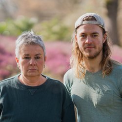 Grüne Fraktionsvorsitzende Suse Stobbe und Julian Schlumberger, vor unscharfem rötlich-grünen Hintergrund