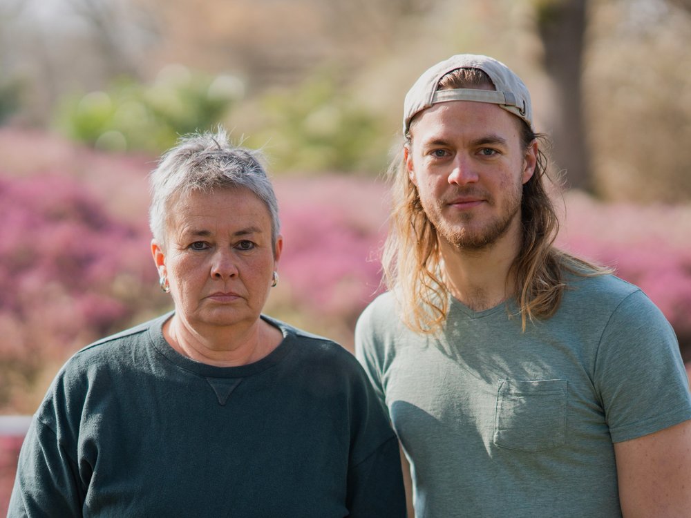 Grüne Fraktionsvorsitzende Suse Stobbe und Julian Schlumberger, vor unscharfem rötlich-grünen Hintergrund