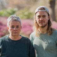 Grüne Fraktionsvorsitzende Suse Stobbe und Julian Schlumberger, vor unscharfem rötlich-grünen Hintergrund