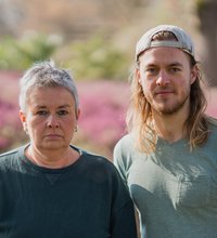 Grüne Fraktionsvorsitzende Suse Stobbe und Julian Schlumberger, vor unscharfem rötlich-grünen Hintergrund