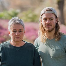 Grüne Fraktionsvorsitzende Suse Stobbe und Julian Schlumberger, vor unscharfem rötlich-grünen Hintergrund